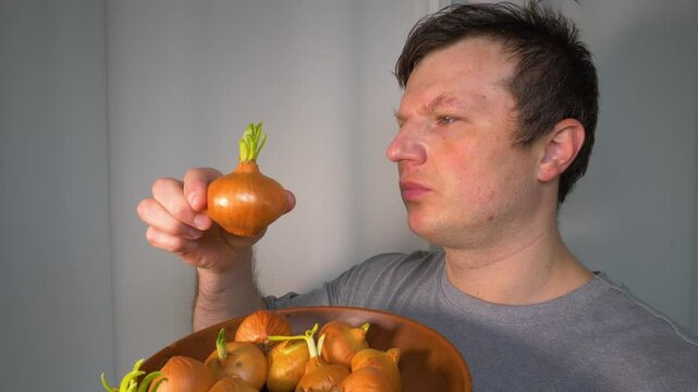  A man holds a plate with onions with green sprouts. Onion vegetable in a man's hands. Slow motion. On a white background.