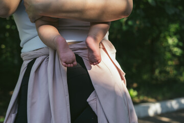 Woman hand is holding bare baby feet, close-up view. Hugging her newborn son or daughter. 