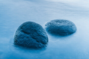 Stones on calm sea at Biskopshagens Nature Reserve in Sweden during serene twilight