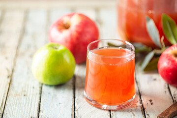 Glass of fresh apple juice and red apples on wooden background