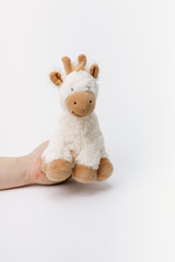 Baby giraffe stuffed animal sitting on a white background