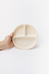 Hand holding beige silicone plate for toddlers