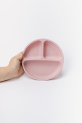 Hand holding pink silicone plate for toddlers