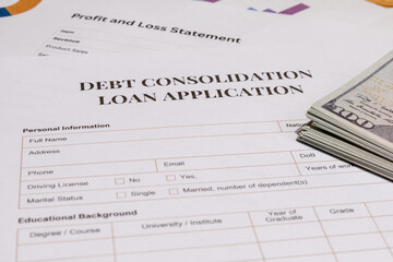 A scene showing official debt consolidation loan application paperwork placed on a wooden desk with...