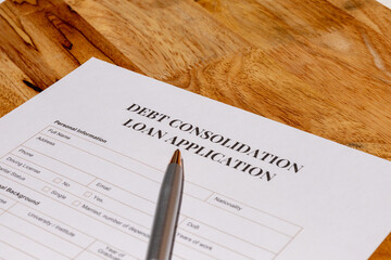 A scene showing official debt consolidation loan application paperwork placed on a wooden desk with...
