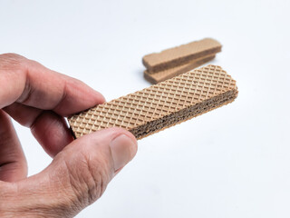 Hand Holding a Chocolate Wafer Cookie Against a White Background
