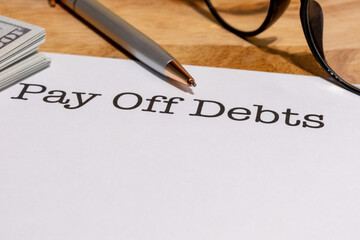 Pay Off Debts Document with Pen and Eyeglasses – Personal Finance and Budget Planning Concept