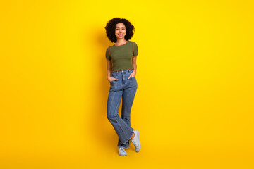 Fototapeta premium Young stylish woman in casual attire standing confidently against a yellow background, exuding charm and positivity
