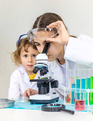 Laboratory examination of a child with test tubes, reagents and a microscope. Selective focus.