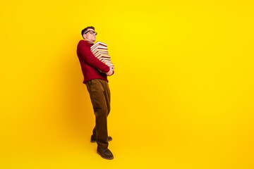 Young Intelligent student Man Holding a Stack of book on a Bright Yellow Background
