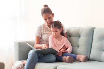 Madre joven leyendo un cuento a su hija fomentando la lectura y desarrollando la imaginación.