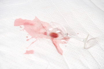 Naklejka premium Broken stemware lies on white textile, causing red stain. High-key lighting enhances contrast. Scene suggests accidental spill and potential cleaning challenge