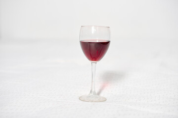 Red wine glass centered on pristine white background. Minimalist composition and even lighting highlight deep, rich red wine color, evoking elegance and refinement