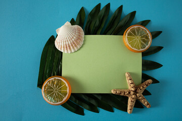 Green paper on a palm leaf decorated with lemon, shell and starfish