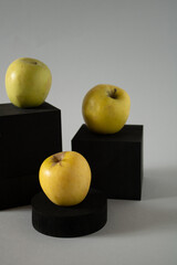Black geometric blocks in a shop window with three fresh organic apples on them