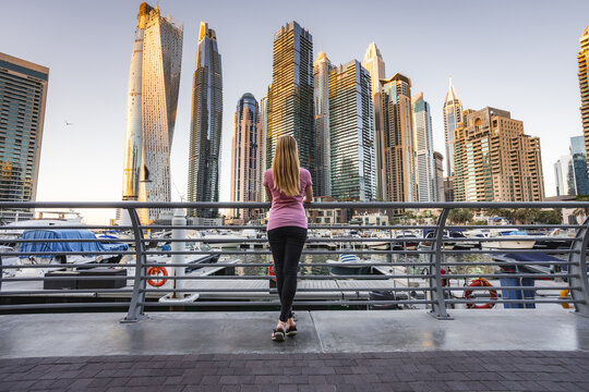 Woman looking up in awe at the towering skyscrapers of Dubai Marina.