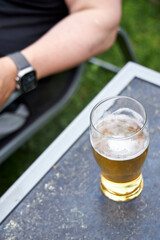 A man sitting outdoors holding a glass of beer in his hand