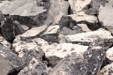 Asphalt broken into large pieces on the road. Repair work in the city. Road repair work. A mountain of removed asphalt pavement. Repair concept. A pile of asphalt debris close-up