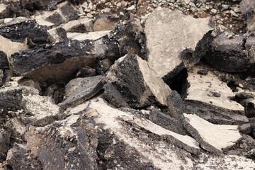 Asphalt broken into large pieces on the road. Repair work in the city. Road repair work. A mountain of removed asphalt pavement. Repair concept. A pile of asphalt debris close-up