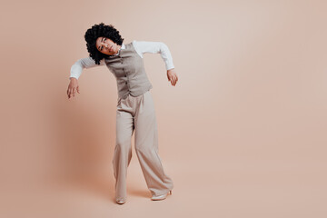 Stylish businesswoman in professional attire posing confidently against a pastel beige background