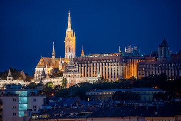 Naklejka premium Night view of Matthias Church (The Church of Our Lady) in Fisherman's Bastion in Budapest, Hungary, beautifully illuminated against the dark sky, showcasing its architectural details