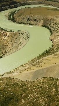 Meandering river in hilly valley fpv drone. Mountain entrenched stream course hidden between sloppy banks at highland area. Watercourse observing
