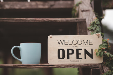 A coffee shop with a welcome sign posted through the glass door, ready to serve customers.	