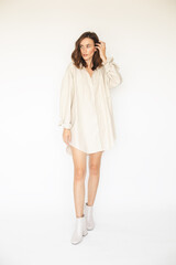 Attractive brunette woman wear beige shirt dress. Street fashion. Model wearing sexy outfit. Details of everyday elegant look. Sexy brunette woman with curly short hair walking and posing.