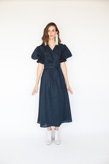 Attractive brunette woman wear navy blue dress with long cuffed puff sleeves and silver beads earrings. Sexy brunette woman with curly short hair look sensual.