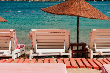 summer vibes on sunny hot windy day at beach club with pink umbrellas and sunbeds, amazing nature...