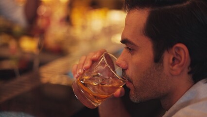 Sitting smart man drinking alone of cocktail Old fashioned waiting friends or couple at bokeh lighting at luxurious beverage counter nightclub at pub and restaurant on Friday meeting night. Vinosity.