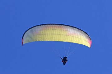 Tandem Paraglider flying in a blue sky	
