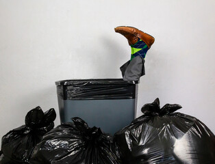 Businessman Stuffed in Trash Can Surrounded by Pile of Garbage Bags. Over a Barrel. Concept of Being Sacked or Fired.