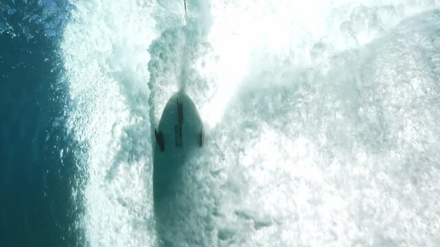Underwater shot of blue barreling wave with silhouette of surfer in the barrel riding in slow motion. Tahiti famous surf destination for surfers, French Polynesia. 