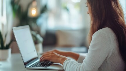 A person seated, typing on a laptop computer.