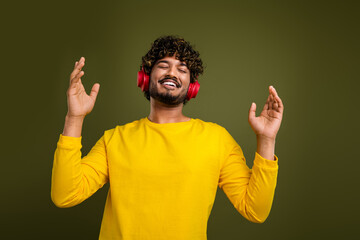 Young man wearing headphones enjoying music with a joyful expression, showcasing happiness and...
