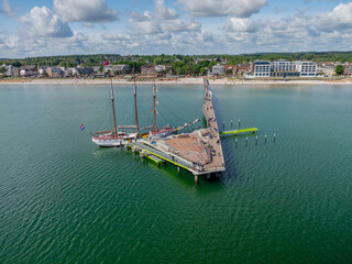 Aerial view of sailing ship docked at the long pier in Scharbeutz on the Baltic Sea. Wooden pier...