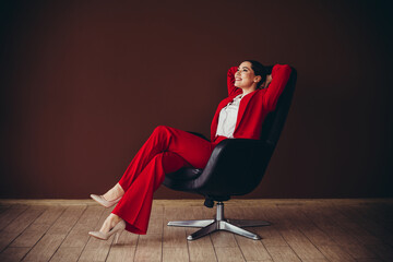 Stunning Confident Businesswoman Relaxing in a Stylish Office Setting Wearing Elegant Red Suit