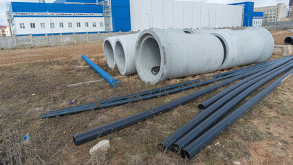 Construction site showcasing various diameters of polyethylene and concrete pipes for water supply....