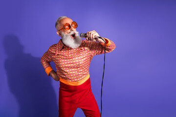 Plakat Extravagant elderly man with vibrant retro style singing passionately on microphone, showcasing vintage fashion
