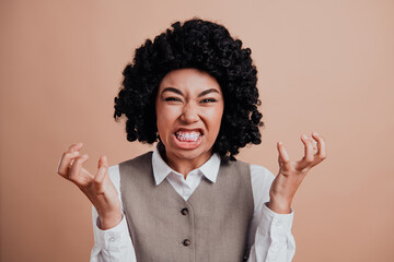 Confident businesswoman posing with expressive emotions and unique black curly hair against a beige...