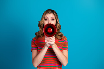 Obraz premium Young woman holding megaphone making announcement against blue background with expressive posture and cheerful expressions