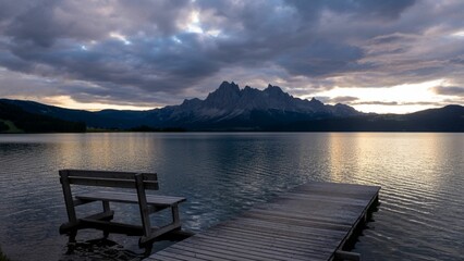 Obraz premium Serene sunset at a mountain lake with a bench