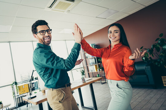 Happy business colleagues celebrating success with a high five in an elegant modern office workspace, symbolizing teamwork and positivity