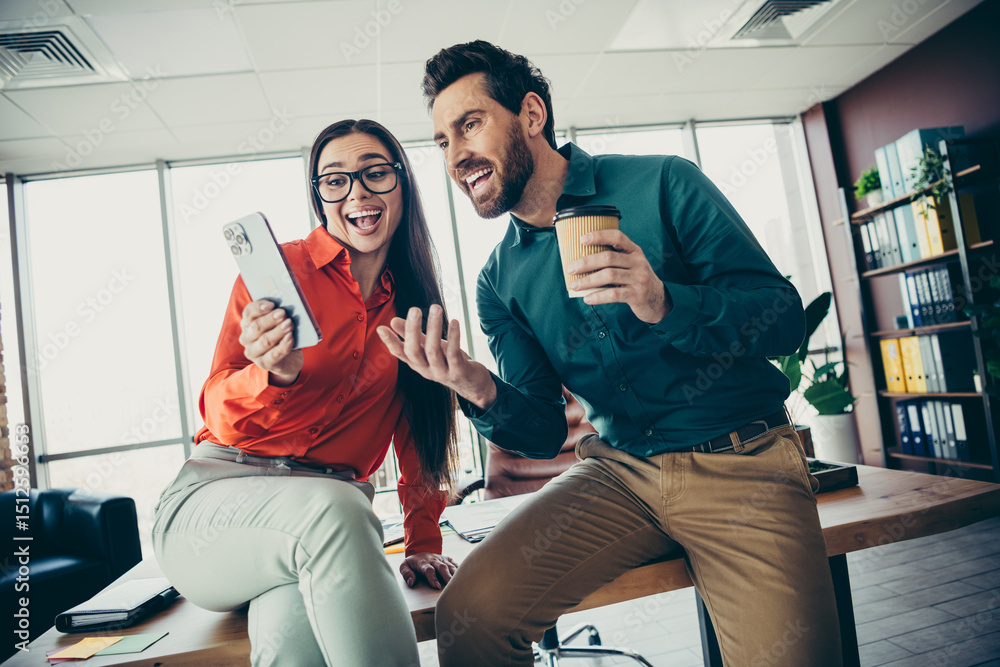 Poster smiling colleagues enjoying a moment of laughter while collaborating at a modern office workspace du