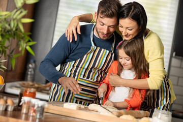 Cheerful family in kitchen baking and happy for weekend break.