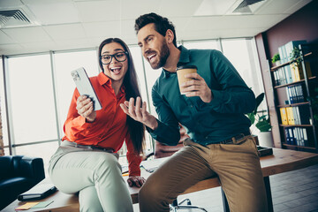 Smiling colleagues enjoying a moment of laughter while collaborating at a modern office workspace...
