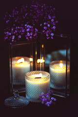 a lit candle surrounded by flowers, with its reflection beautifully captured in mirrors. romantic,...