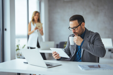 Businessman Working at Desk with Tablet and Coffee in Modern Office