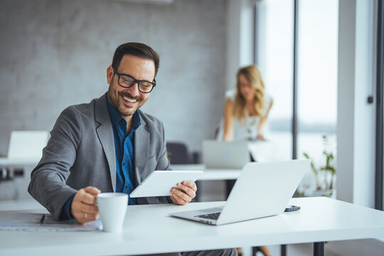 Professional Businessman Smiling While Using Tablet in Modern Office - Powered by Adobe